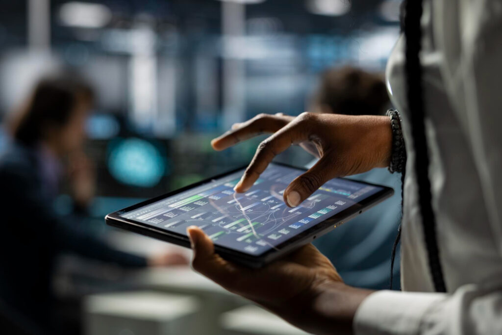 Profissional consultando gráficos de pagamentos em um tablet, ilustrando os testes do split payment com bancos