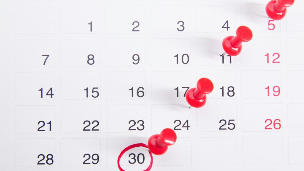 Calendário com alfinetes vermelhos marcando datas, representando os prazos da Reforma Tributária entre o 2º turno e a posse