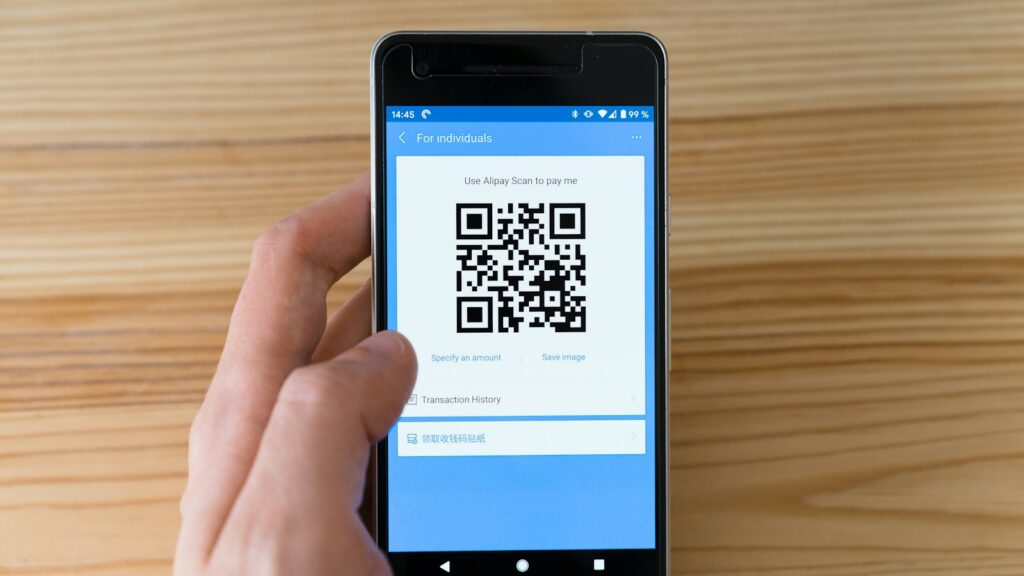 Celular exibindo QR Code de pagamento sobre mesa de madeira, ilustrando o split payment da Reforma Tributária