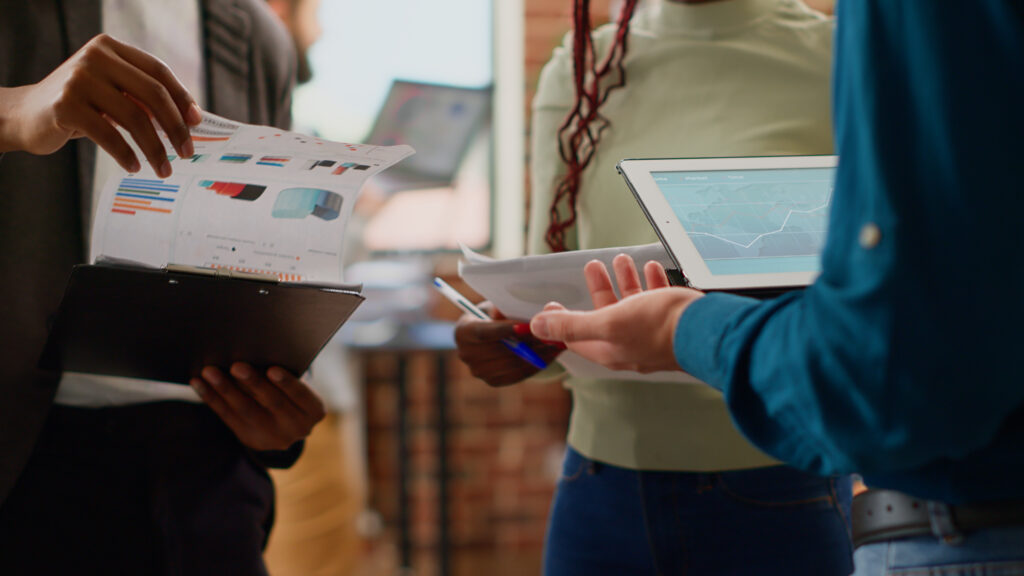 Pessoas analisando gráficos impressos e tablet para recalcular preço e margem com IBS e CBS