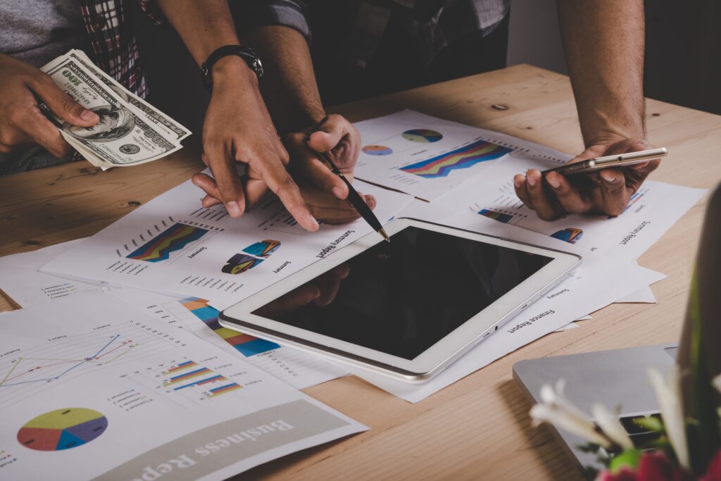 Mãos analisando relatórios financeiros, tablet e cédulas sobre a mesa, ilustrando a recuperação de tributos pagos a maior