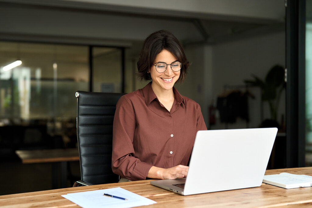 Profissional sorrindo diante do notebook, representando a revisão de tributos dentro do prazo de prescrição