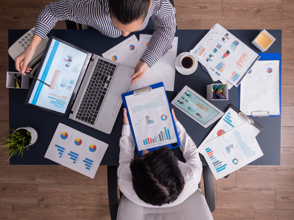 Mesa vista de cima com notebook, prancheta e gráficos, representando o checklist de preparação para 2027